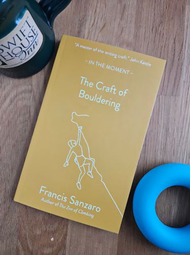 The cover of 'The Craft of Bouldering' by Francis Sanzaro with a coffee mug and blue grip training ring.